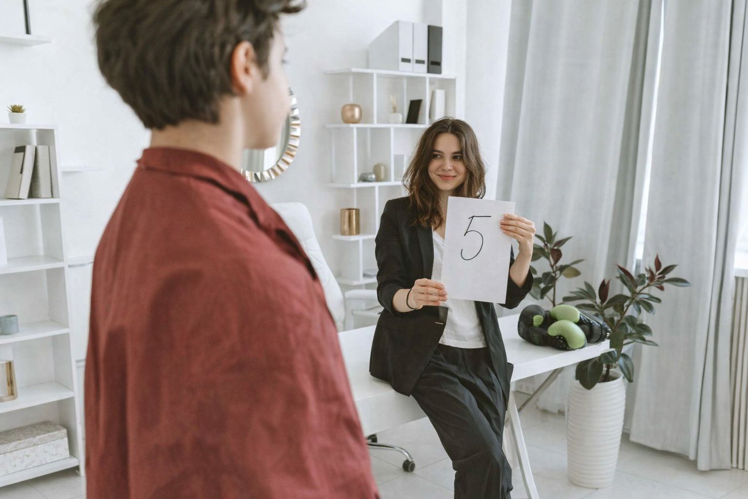 Une femme montre une note sur papier à un adolescent en tenue décontractée.